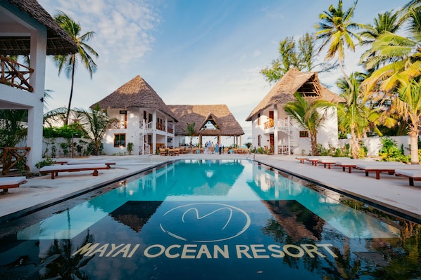 A resort with a pool, thatched-roof buildings, and palm trees. - Mayai Ocean Resort (Bwejuu)