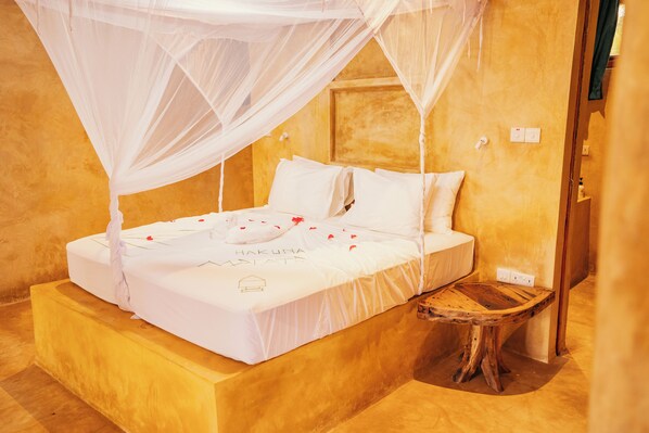 A bed with a canopy, a bedside table, and a wall-mounted outlet. - Mayai Ocean Resort (Bwejuu)