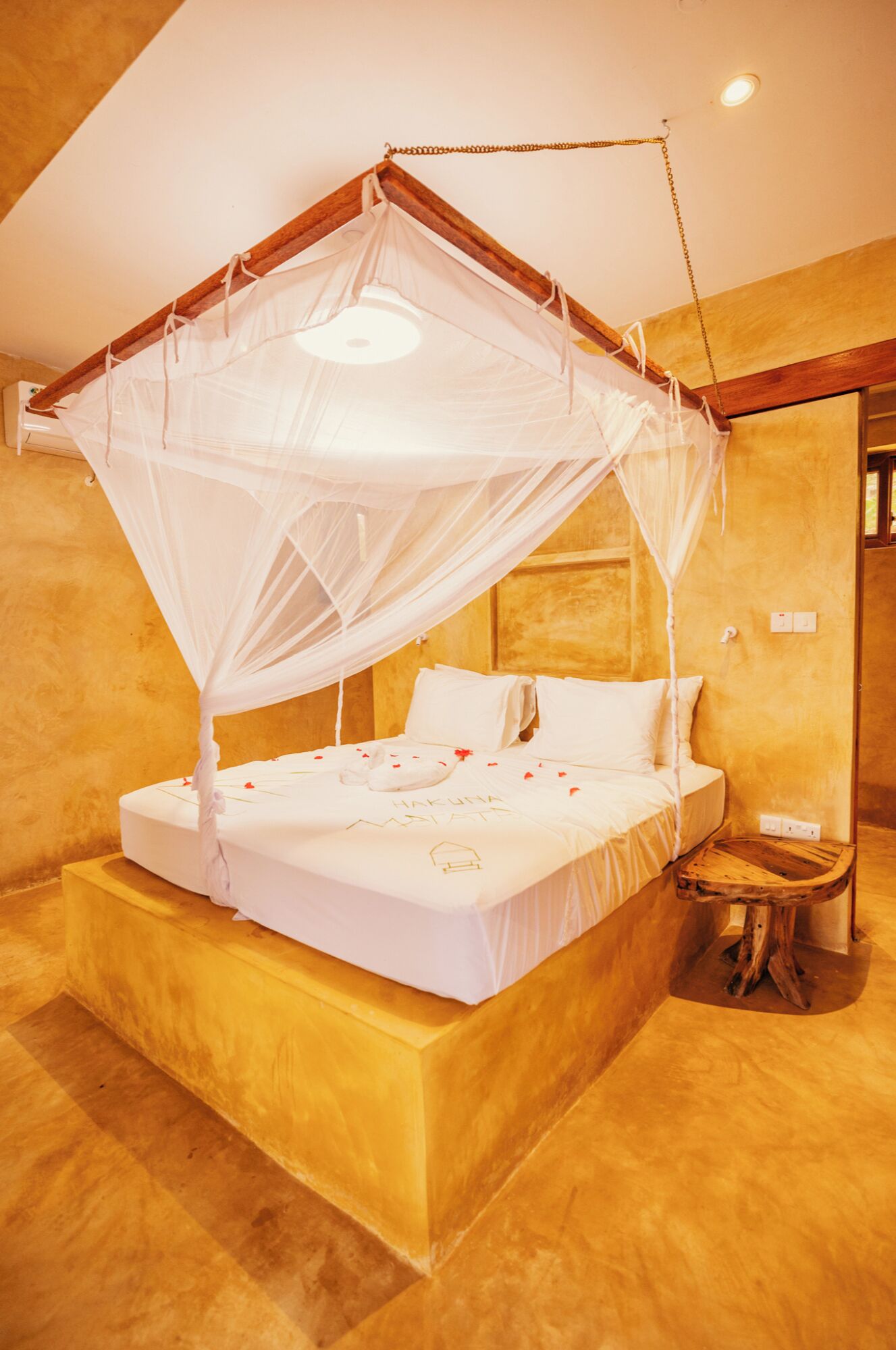 A bed with a canopy, a bedside table, and a small wooden stool.