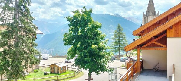 Vista sulle montagne, con un edificio in legno e un albero sullo sfondo.