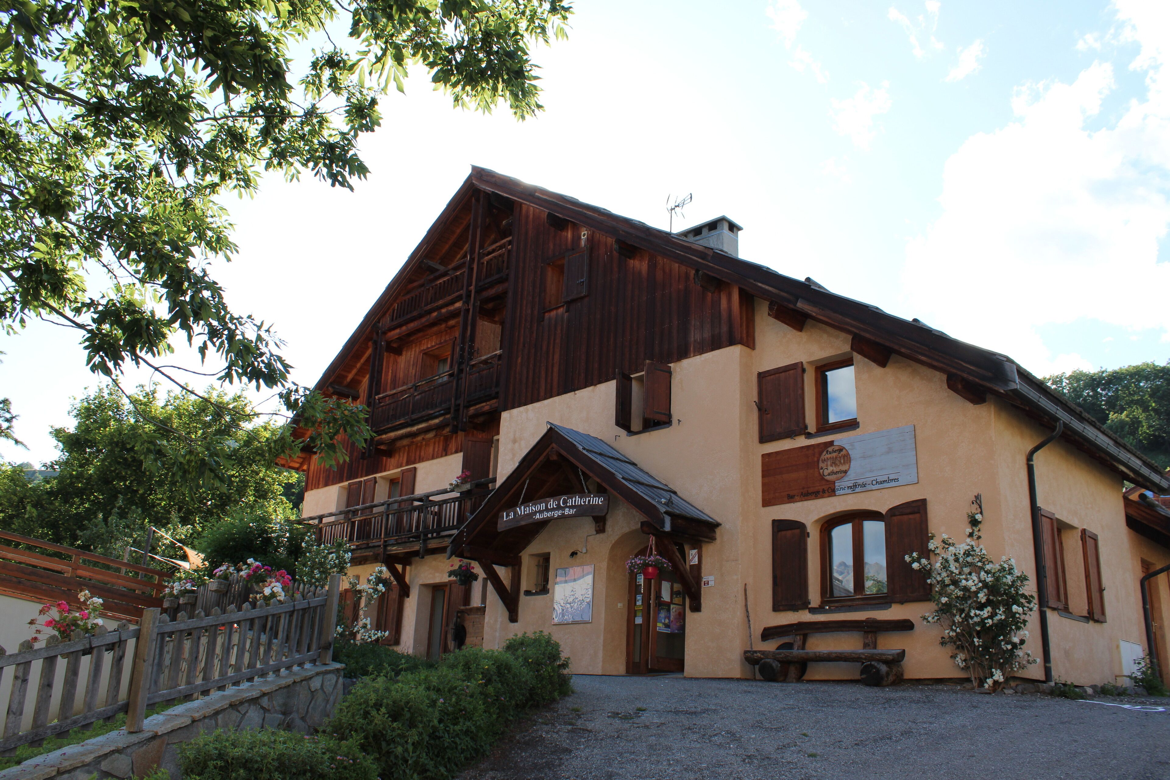 A traditional chalet-style building with a wooden facade, a balcony, and a sign indicating it is a guesthouse.