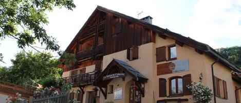 A traditional chalet-style building with a wooden facade, a balcony, and a sign indicating it is a guesthouse.