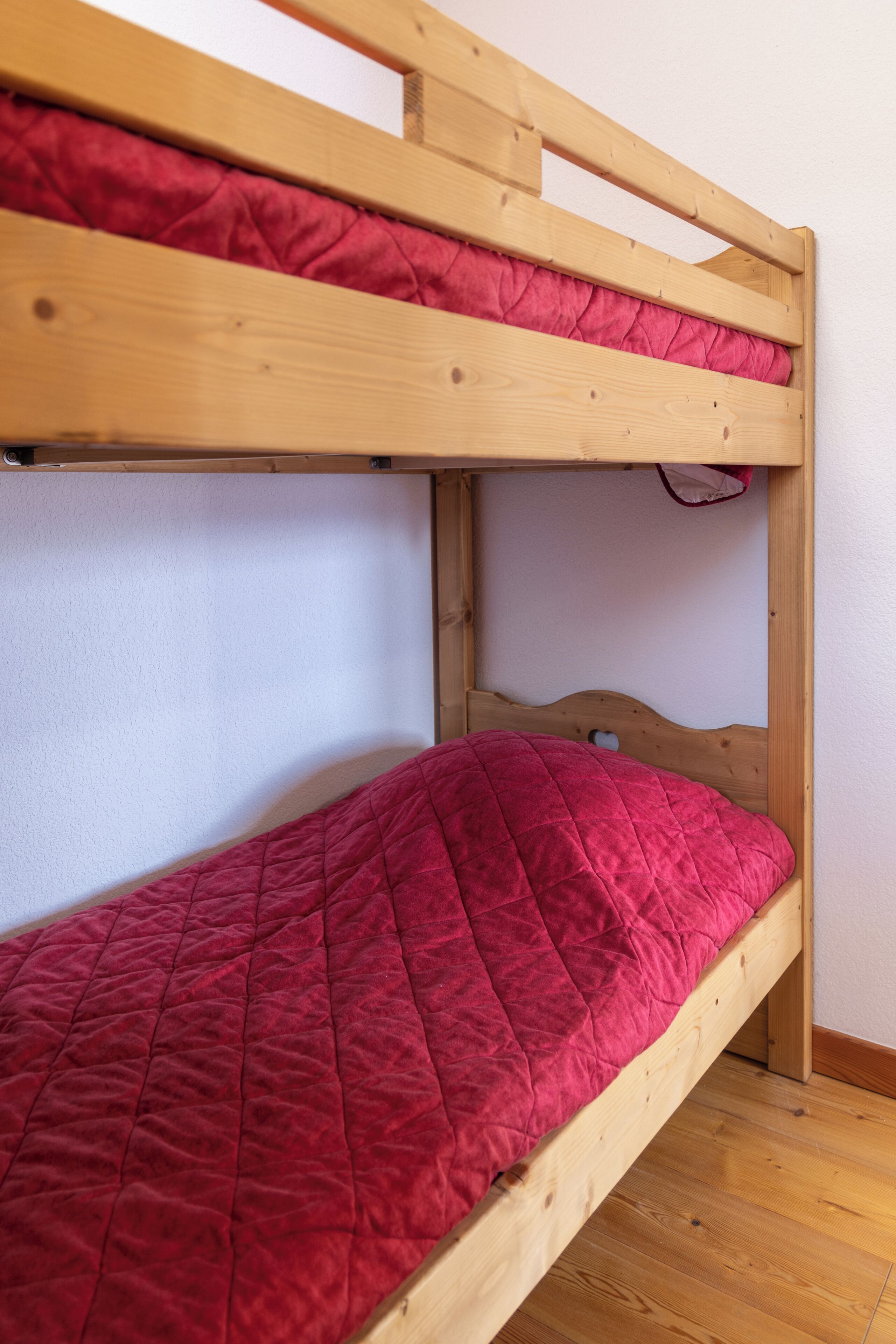 Un lit superposé avec un matelas rouge matelassé et une structure en bois.