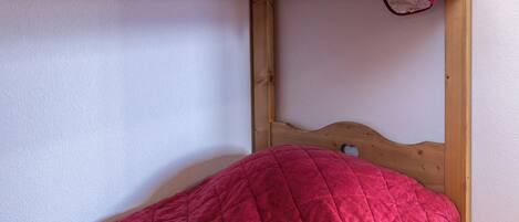 Una cama litera con un colchón acolchado rojo y estructura de madera.