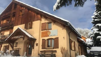 Un edificio de estilo chalé con fachada de madera y tejado cubierto de nieve.