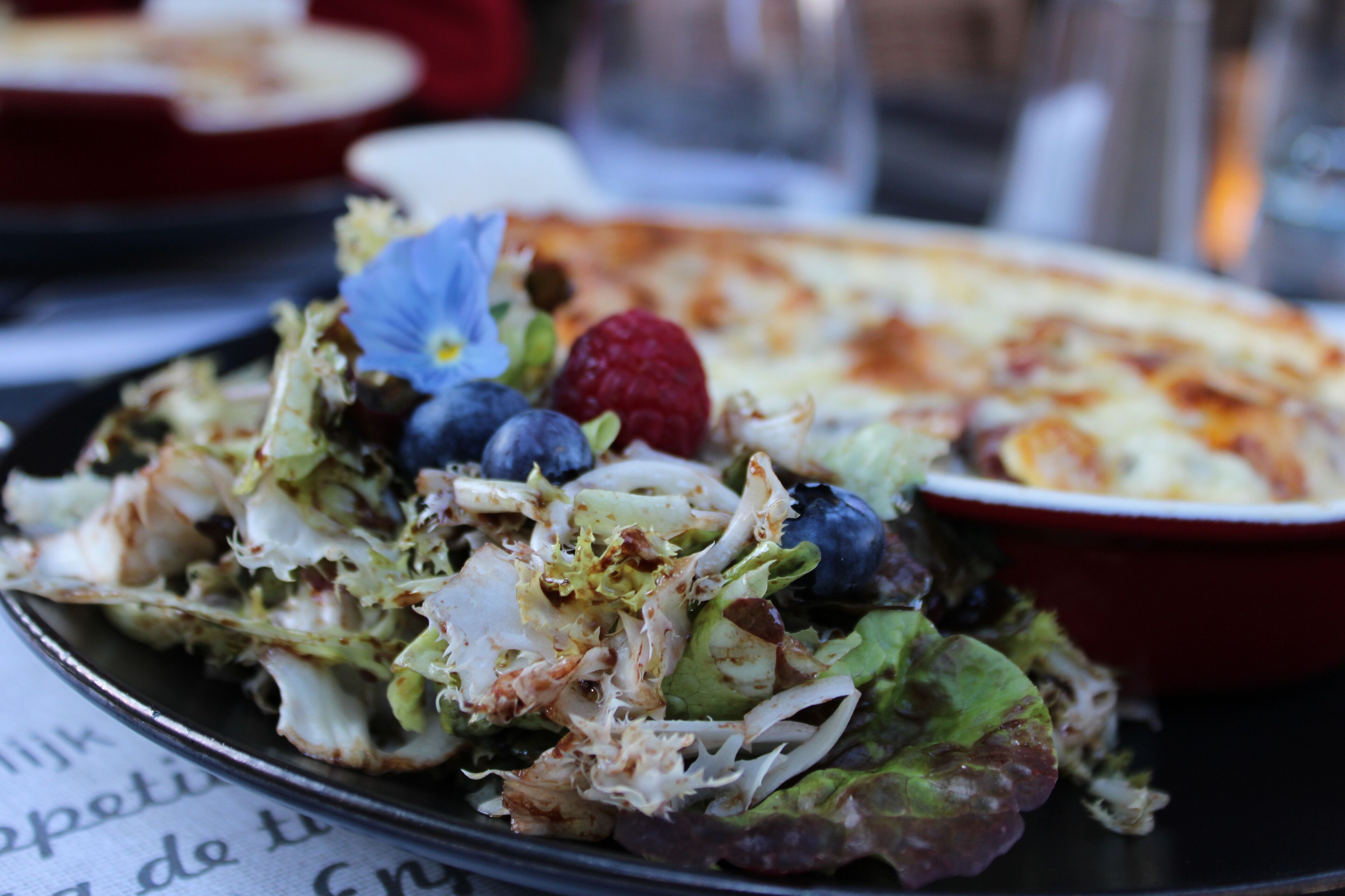 Prato de salada com diversos vegetais e uma fatia de pizza.