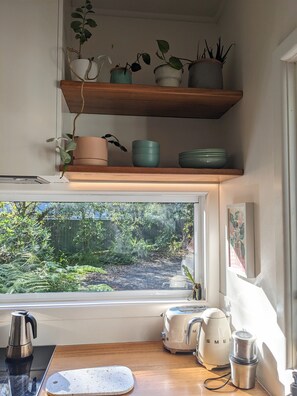 Kitchen area with a view of the lush garden, featuring a coffee maker, toaster, and kettle.