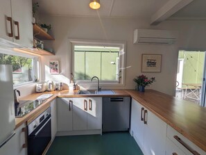 Compact kitchen with modern design, featuring a stainless steel sink, dishwasher, and a window for natural light.