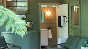 A bathroom with a mirror, towel rack, and a circular light fixture. - Olive-Nature haven, outdoor bath, artistic cottage, 5 mins to Hyams Beach (Old Erowal Bay)