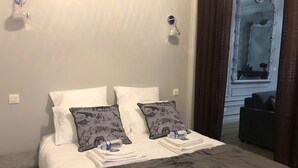 A hotel room with a bed, two pillows with animal prints, a water bottle, and a glass on the bed.
