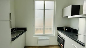 A compact kitchen with a window, a built-in oven, and a microwave.