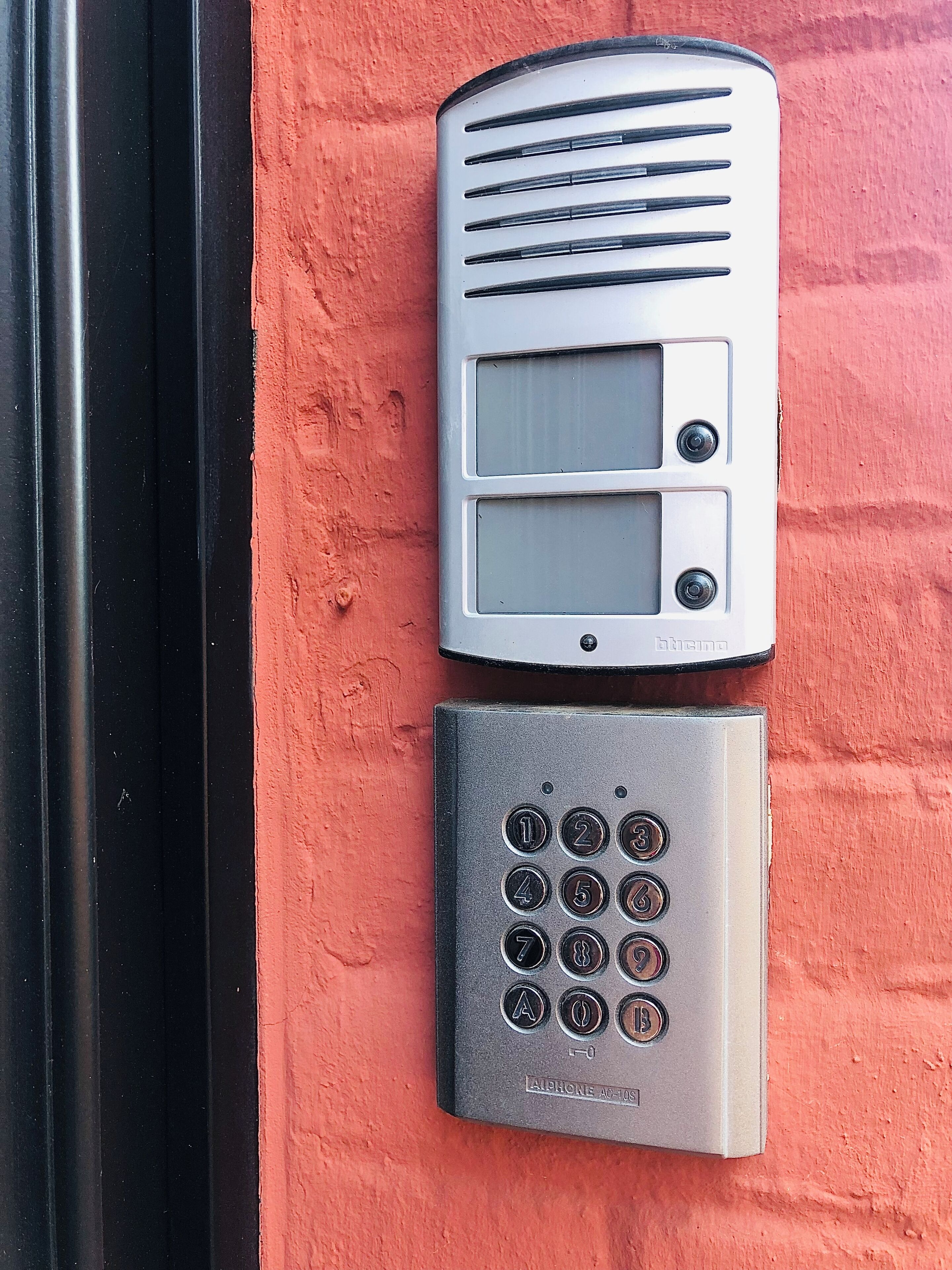 A wall-mounted intercom system with a keypad and a speaker.