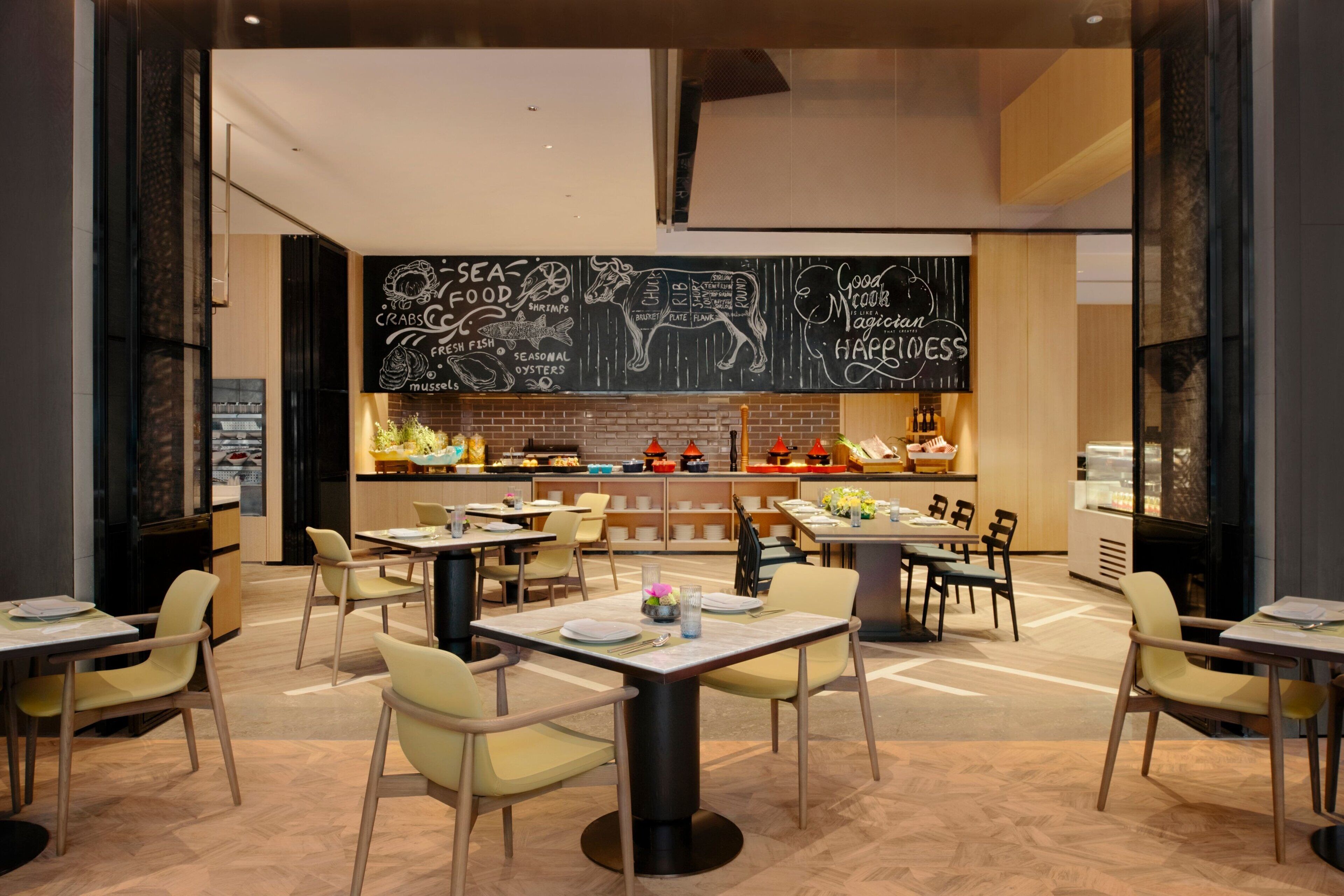 A restaurant with a chalkboard menu, tables, chairs, and a bar area.