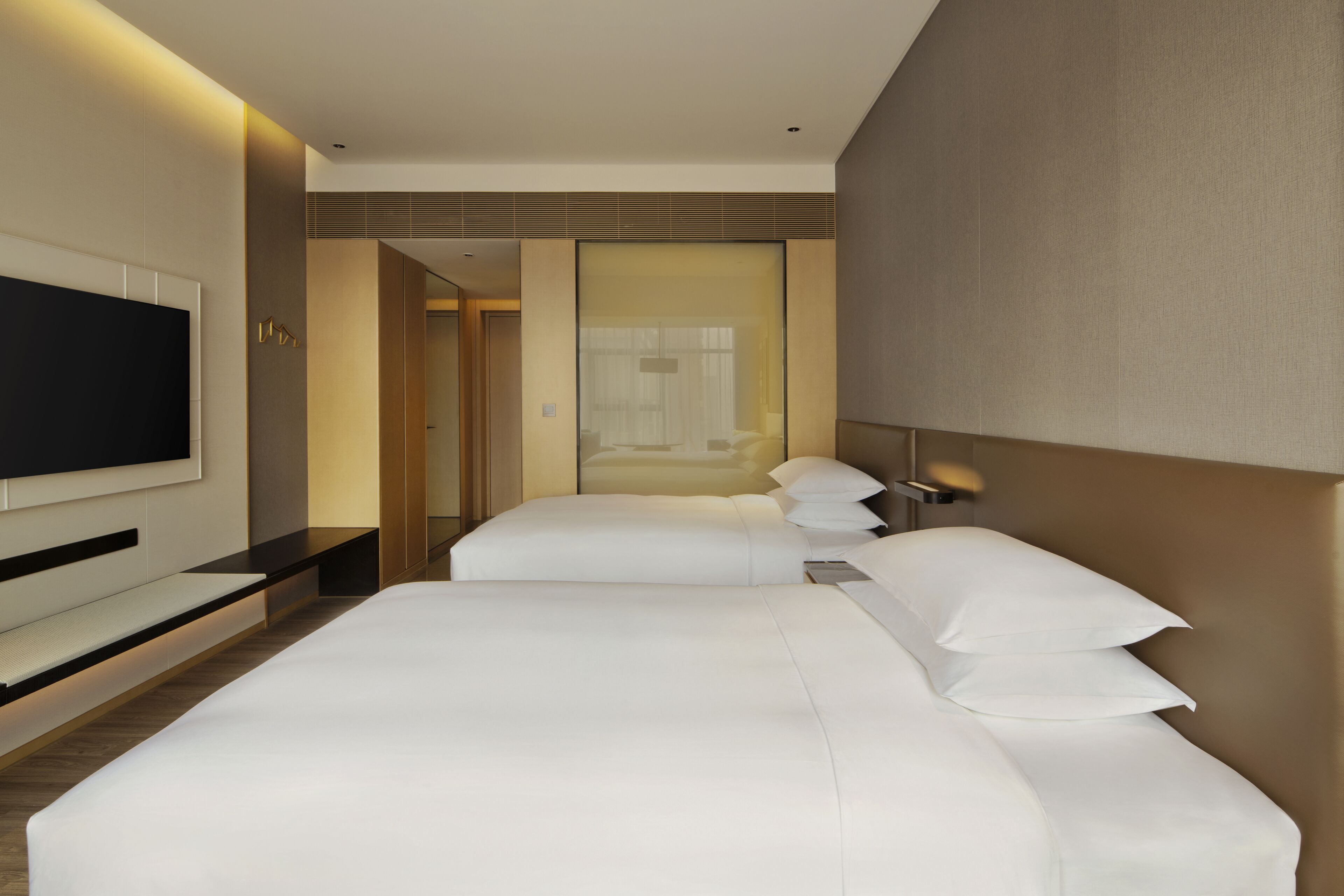 A modern hotel room with a large bed, a flat-screen TV, and a walk-in closet.