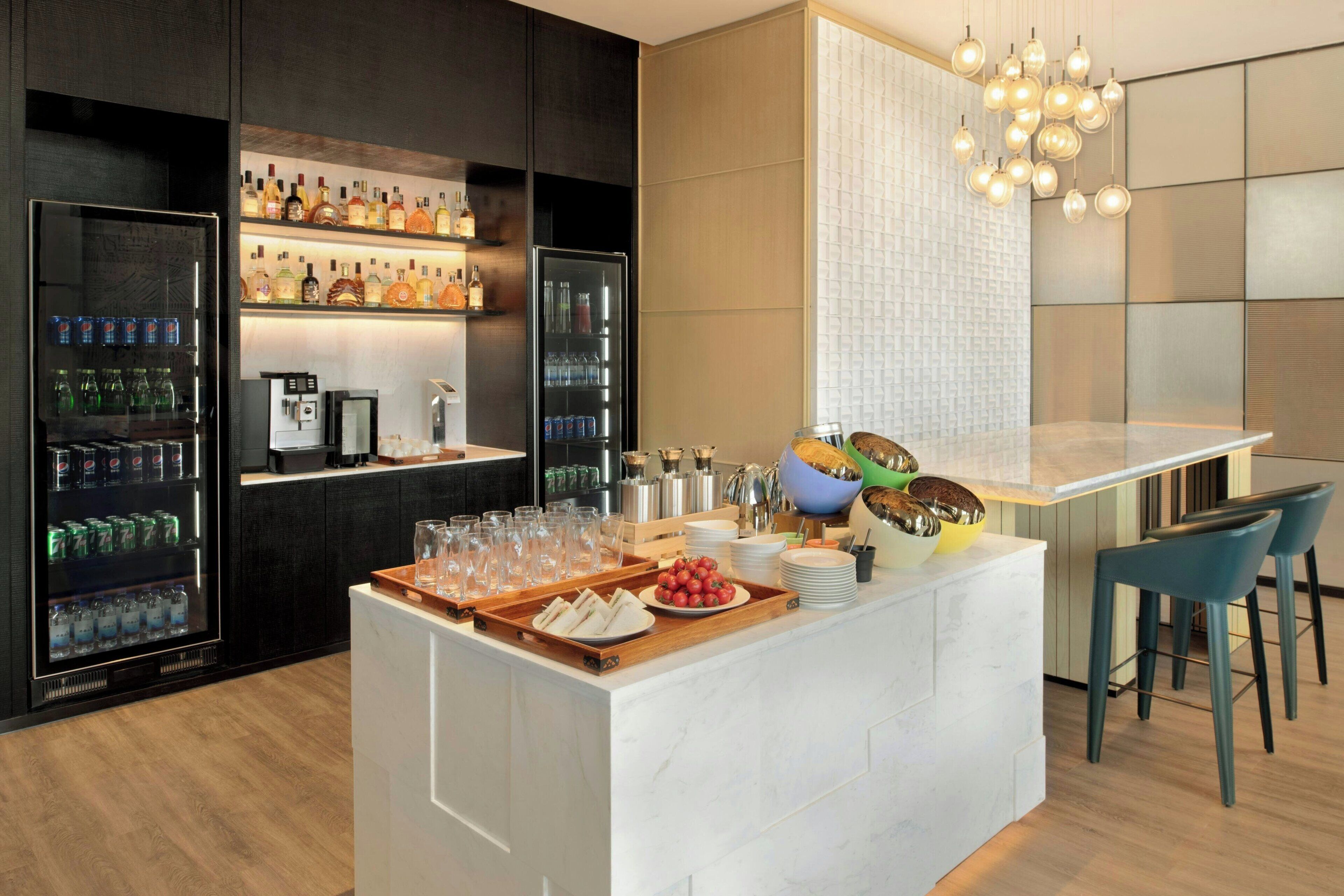 A modern bar area with a variety of beverages, a coffee machine, and a fruit bowl.