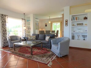 A living room with a sofa, armchairs, a coffee table, and a bookshelf.