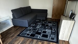 Ein modernes Wohnzimmer mit einem Ecksofa, einem gemusterten Teppich und Holzdielen.