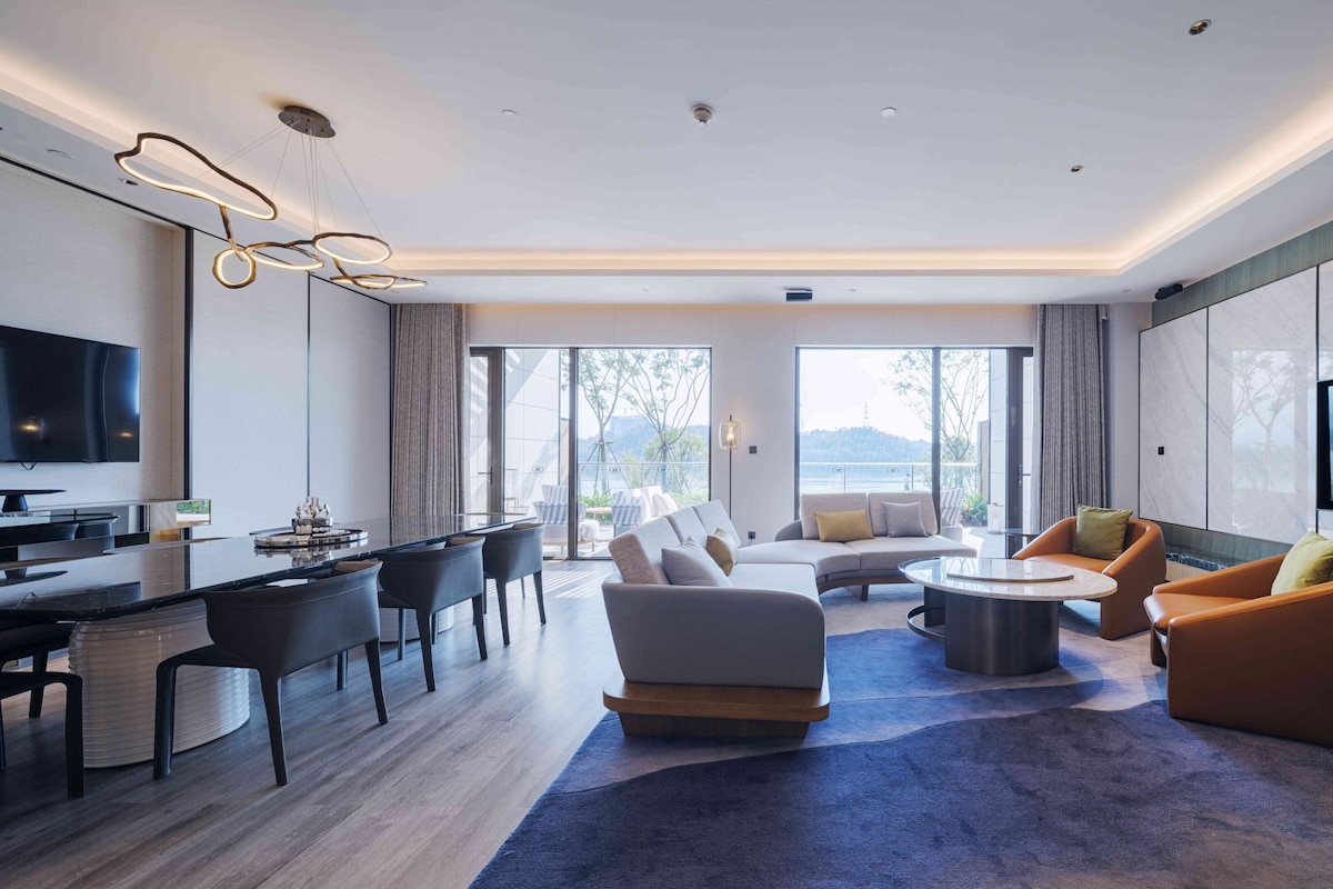 Una sala de estar moderna con comedor, ventanas grandes y un televisor de pantalla plana.