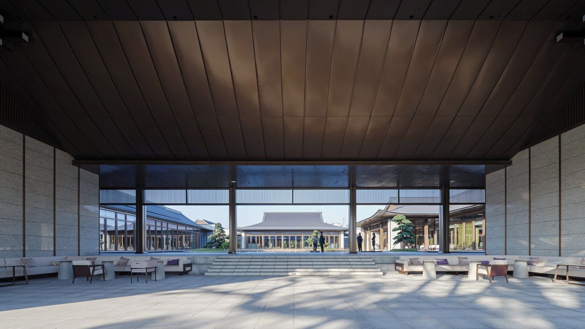 An open-plan lobby with a high ceiling, large windows, and a central staircase.
