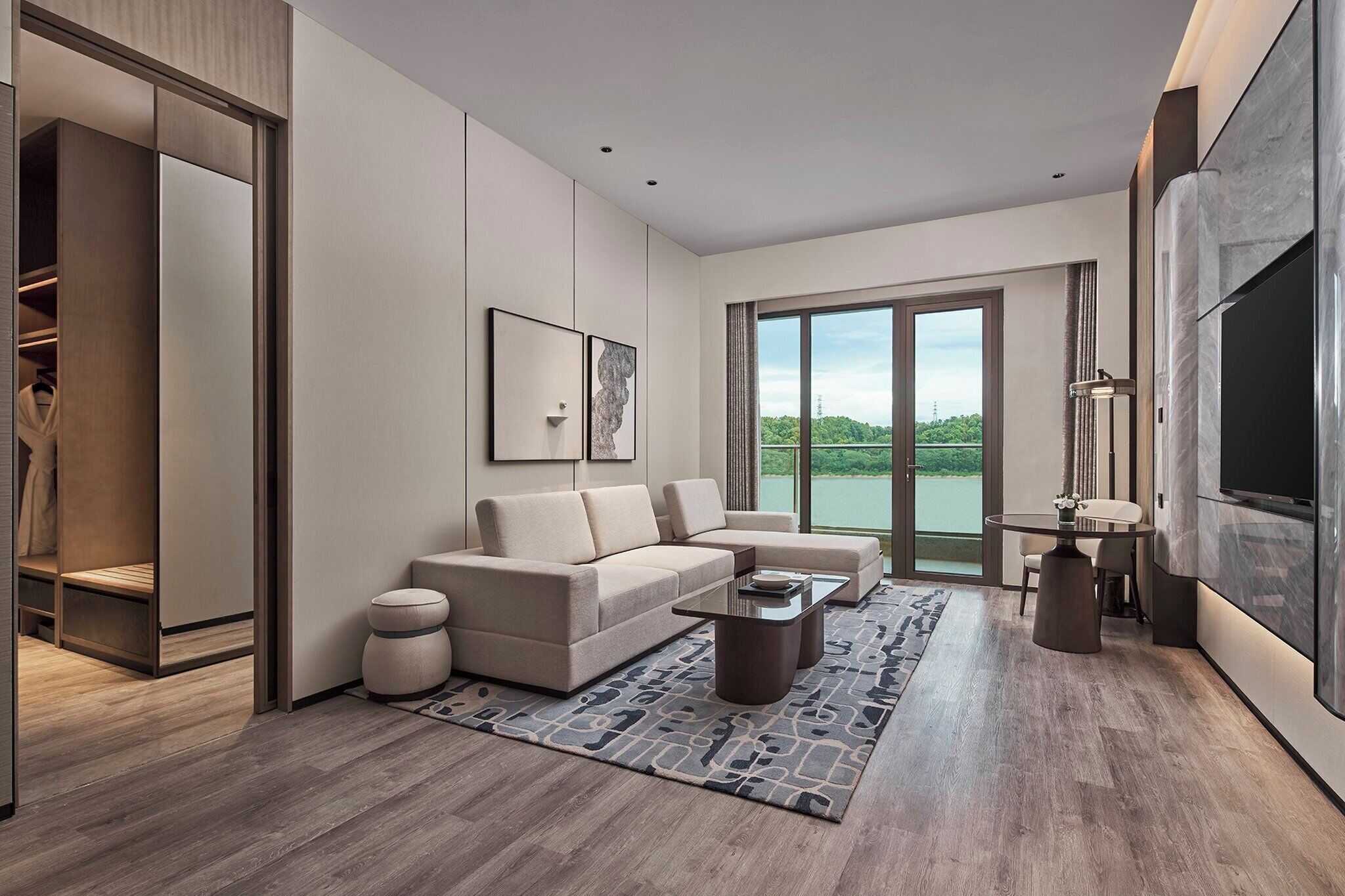 A modern living room with a sofa, coffee table, and a view of a lake through large windows.