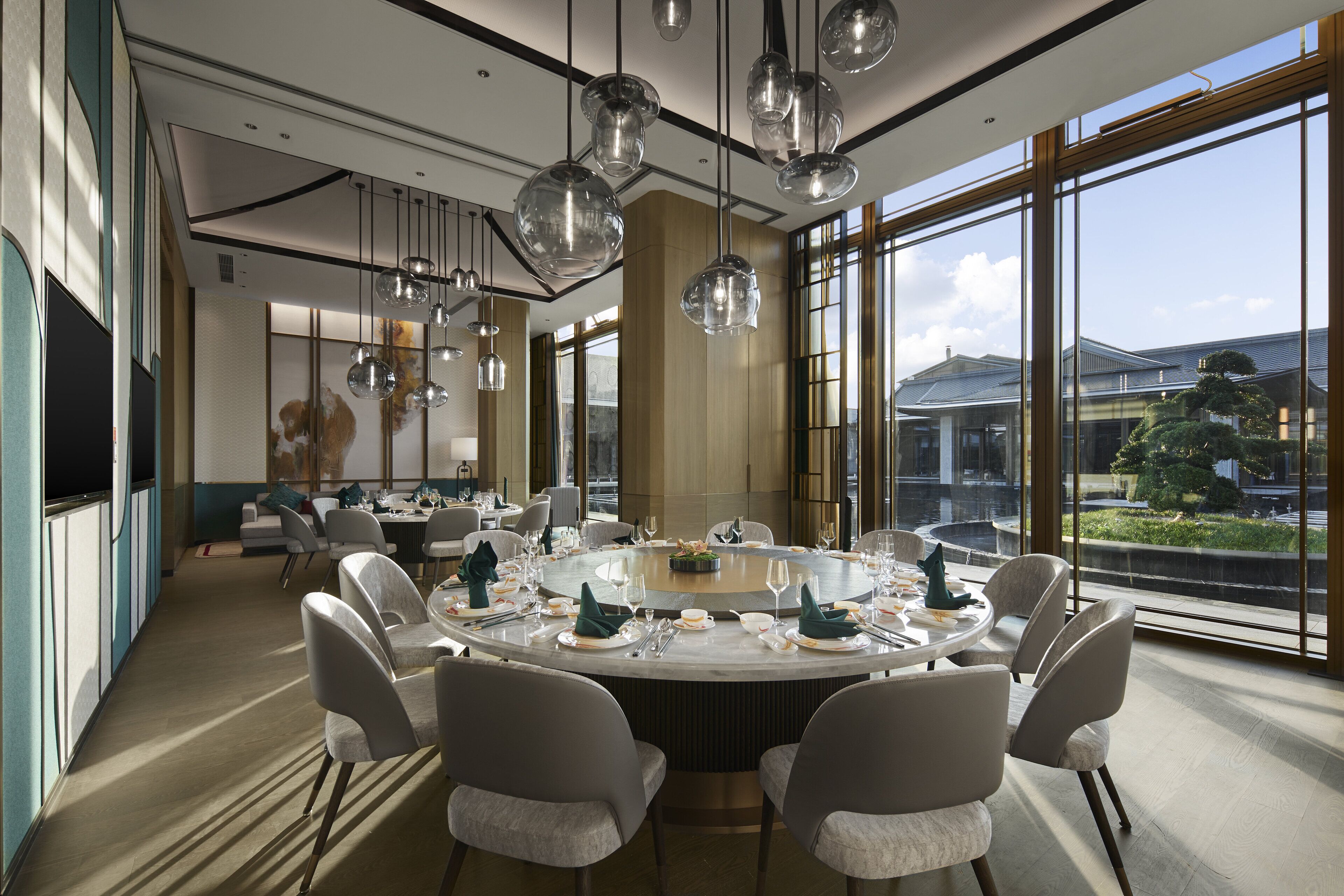A modern dining area with a round table, multiple chairs, and hanging spherical light fixtures.