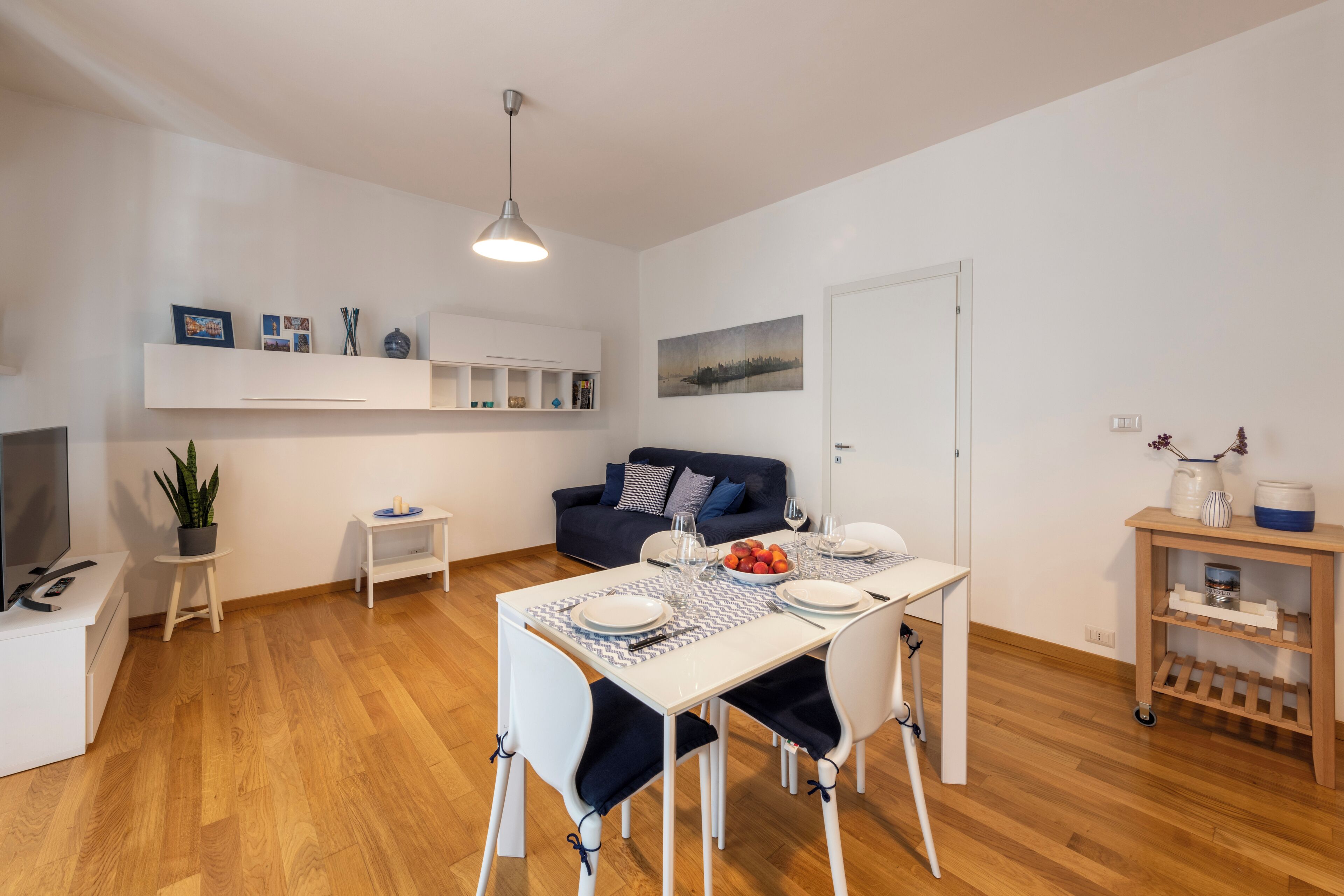 Un salon moderne comprenant un coin repas, un canapé, un téléviseur et un plancher en bois.