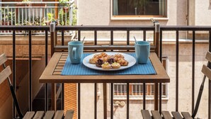 A balcony with a wooden table, two blue cups, and a plate of pastries. - BnButler - Strigelli 13 (Milan)