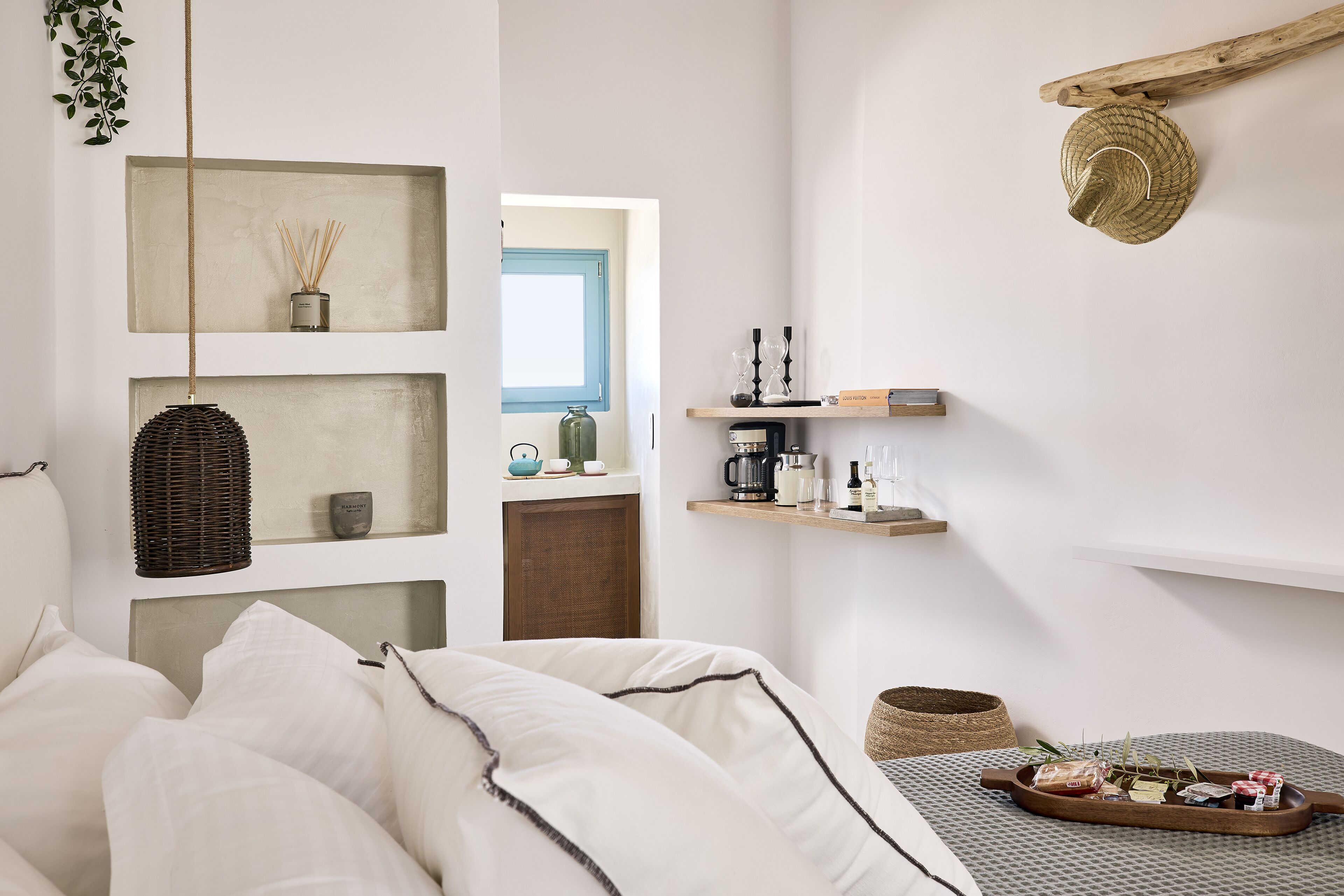 A minimalist bedroom with a bed, shelves with items, and a view into another room.