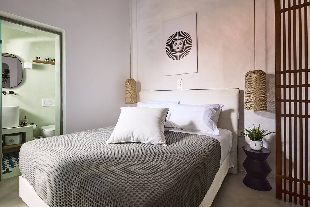 Un dormitorio moderno con una cama grande, una mesita de noche con una planta, una obra de arte en la pared y un armario.
