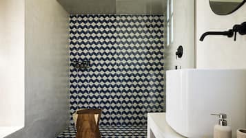 Un baño moderno con un patrón geométrico de azulejos, una bañera grande y un taburete de madera.