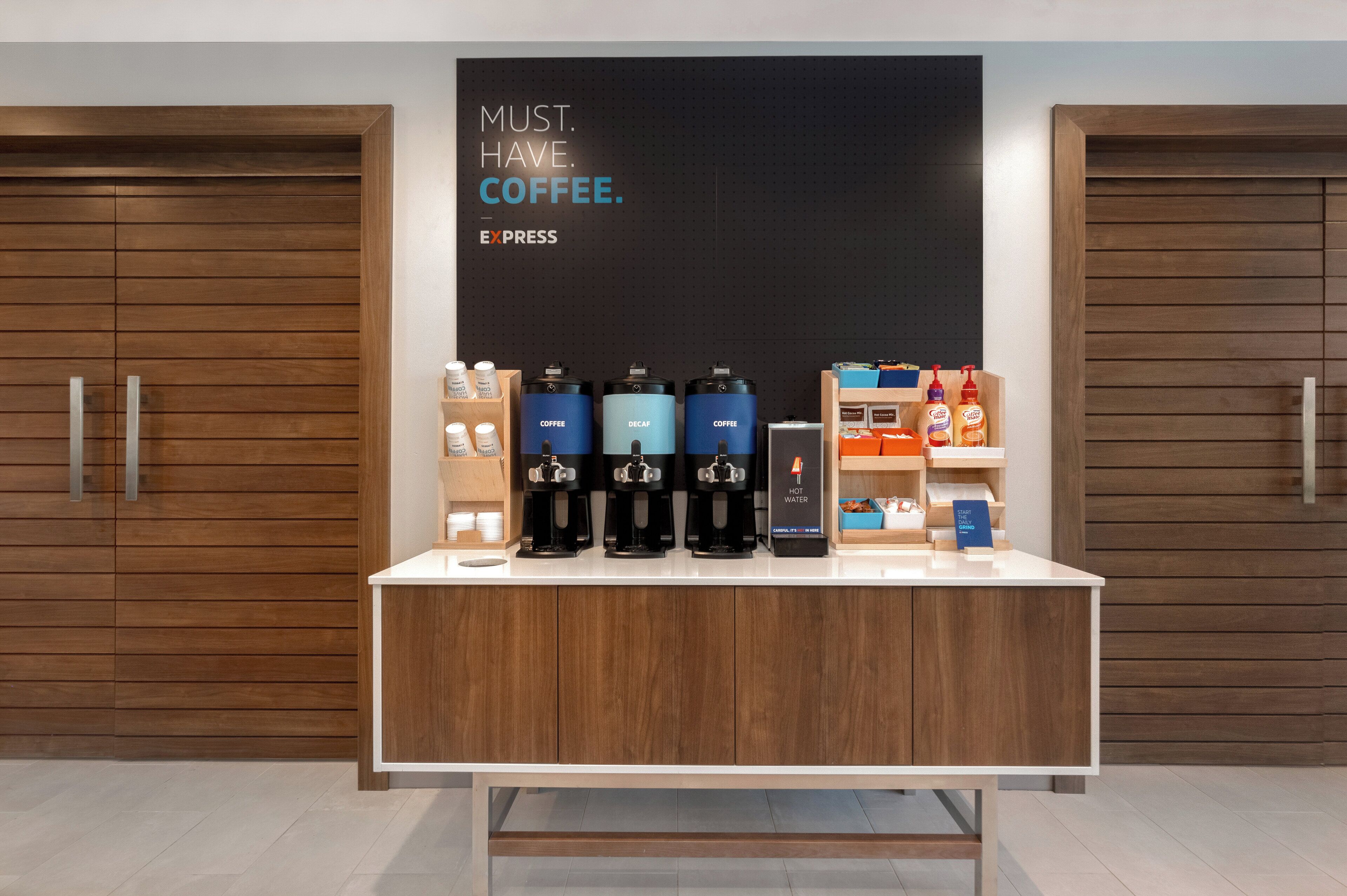 En kaffestation med flere kaffemaskiner og et skilt, der står 'MUST. HAVE. COFFEE. EXPRESS'.