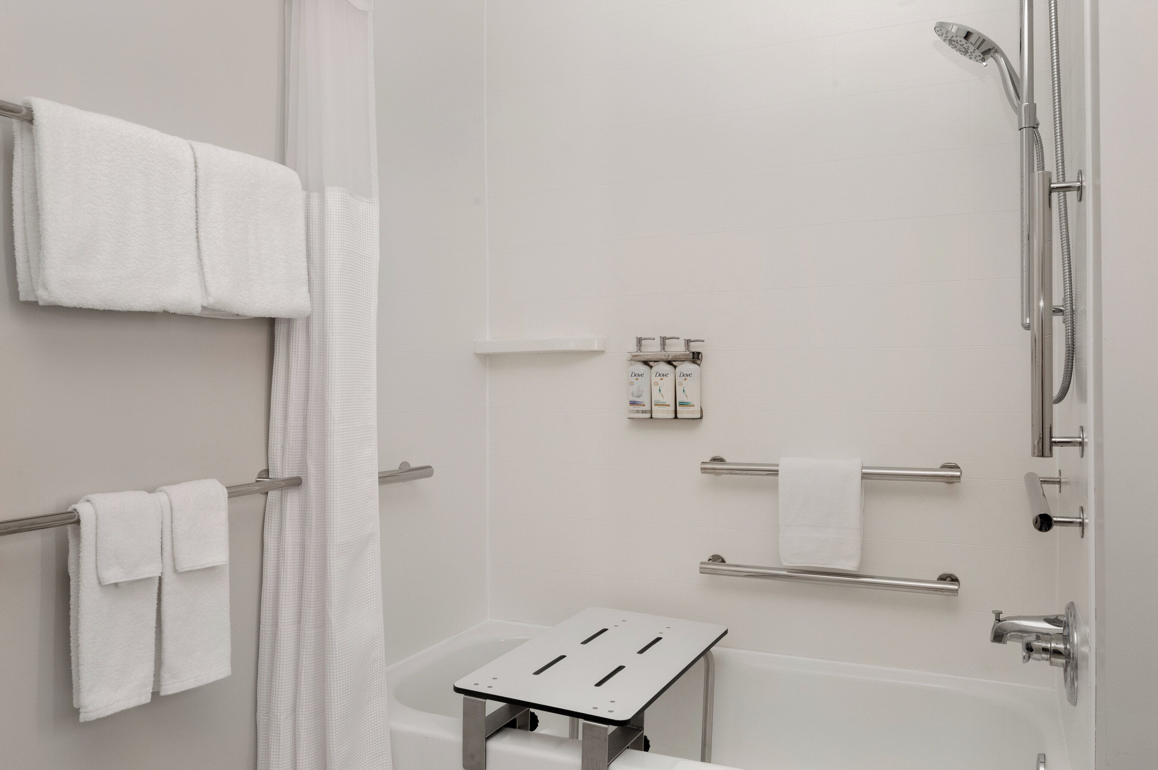 A modern bathroom with a shower, a towel rack, and a small table.