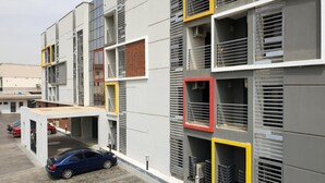A multi-story building with a parking area in front. - MUSADA LUXURY HOTELS AND SUITES (Abuja)