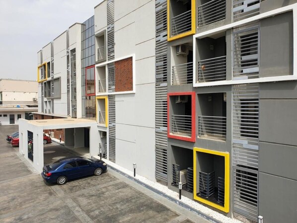 A multi-story building with a parking area in front. - MUSADA LUXURY HOTELS AND SUITES (Abuja)