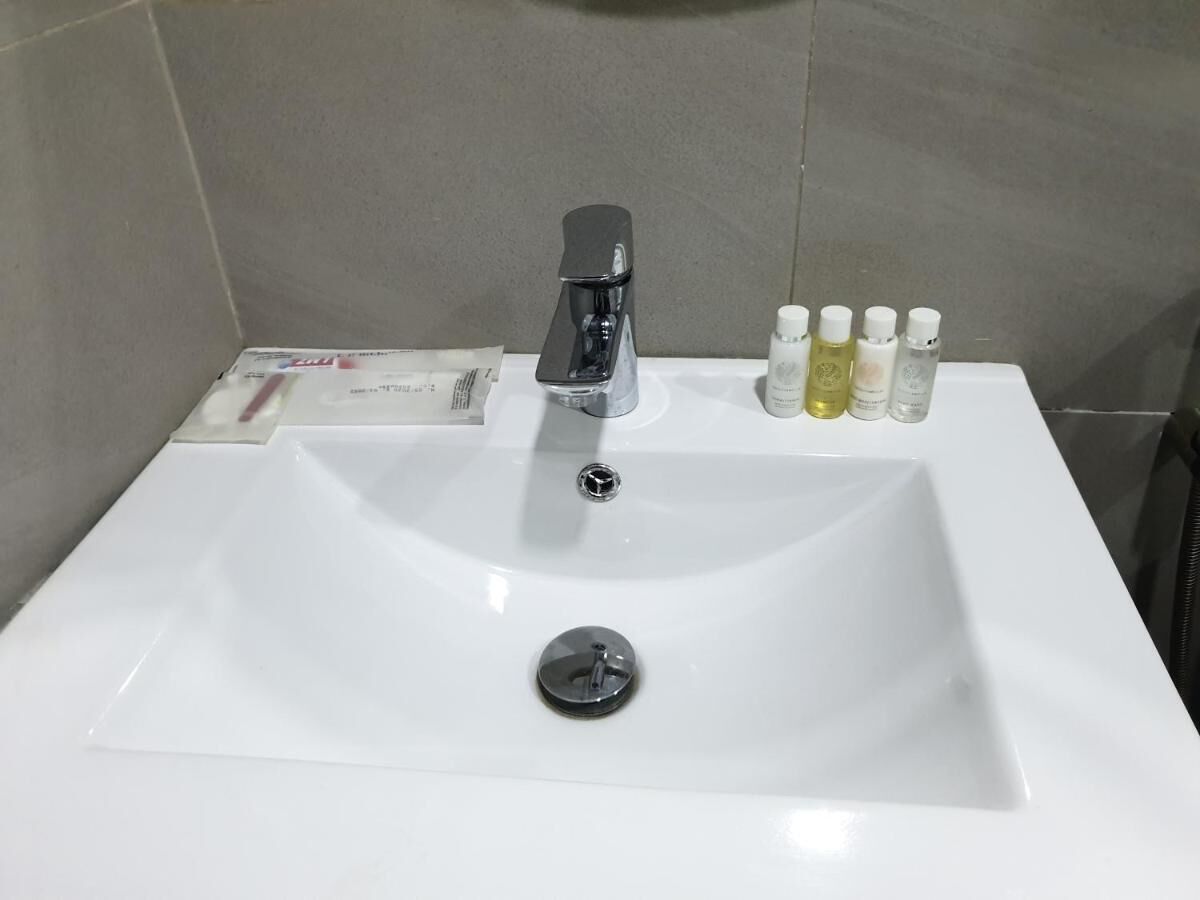 Un lavabo blanc pour la salle de bain, doté d’un robinet moderne, d’un bouchon d’évier et de plusieurs articles de toilette posés sur le comptoir.
