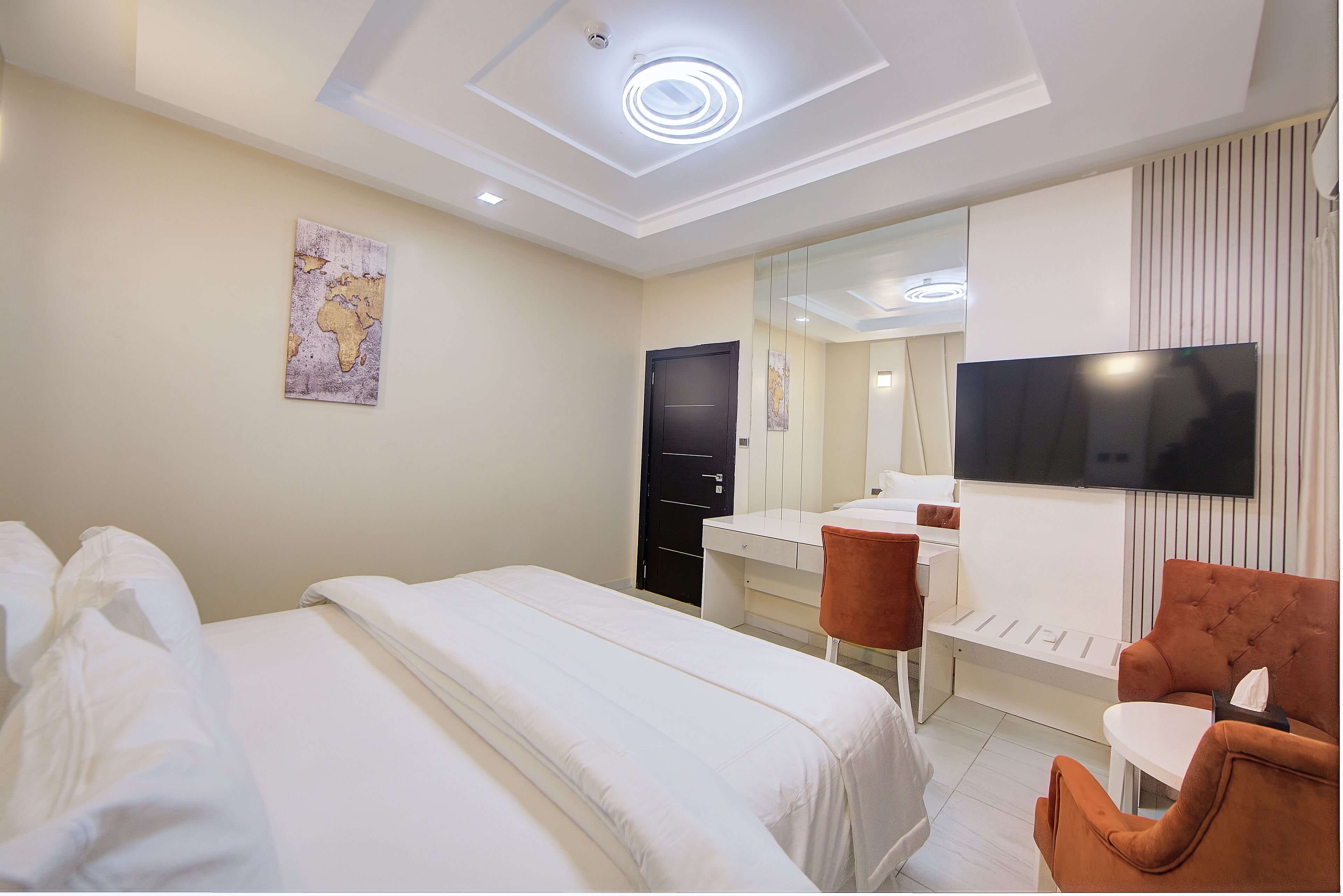 A hotel room with two beds, a TV, a desk, and a mirror.