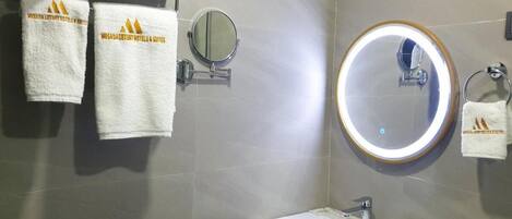 A modern bathroom with a sink, mirror, and towel rack.
