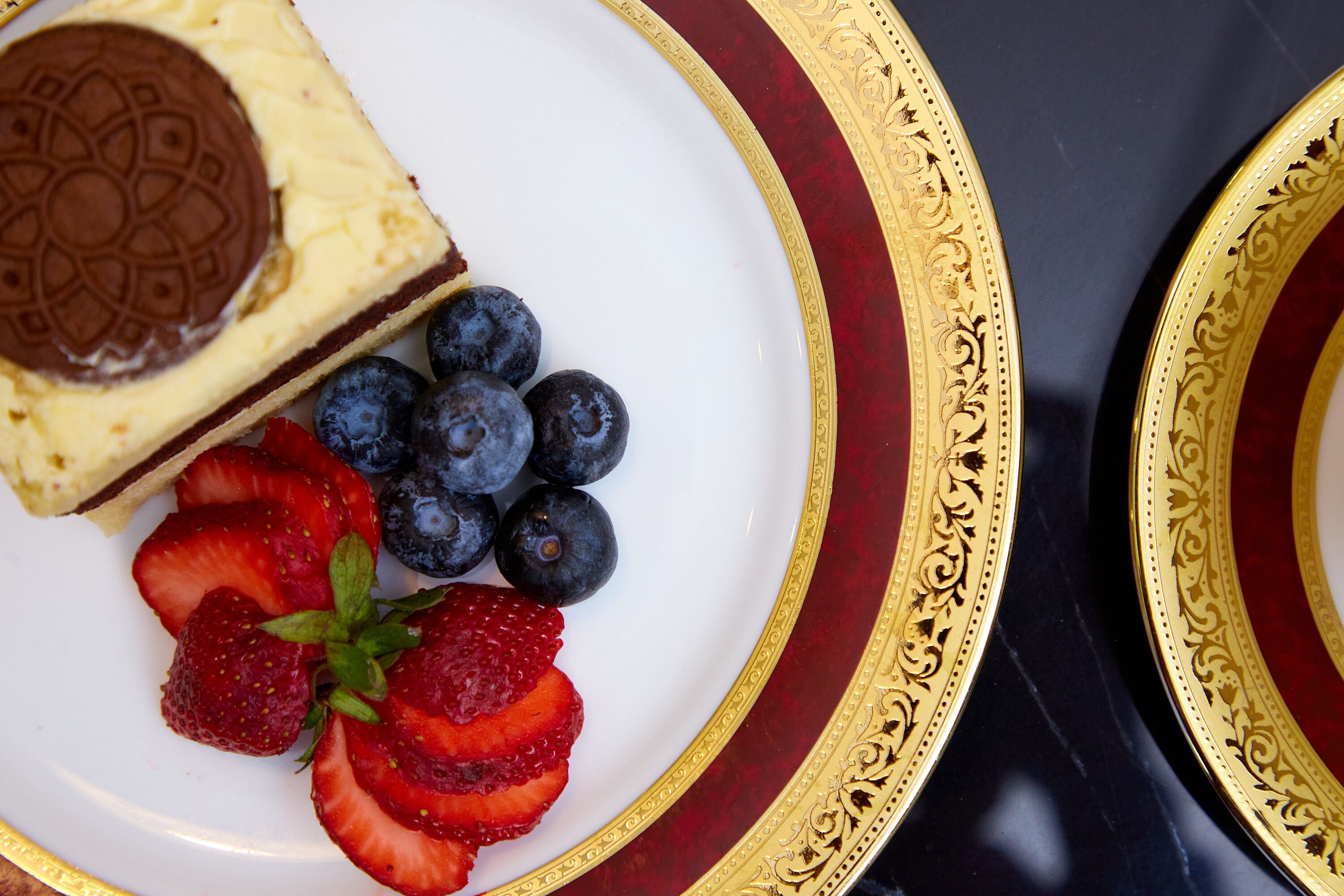 Um prato com uma fatia de cheesecake, mirtilos e morangos.