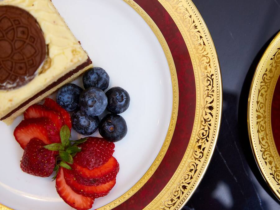 Um prato com uma fatia de cheesecake, mirtilos e morangos.