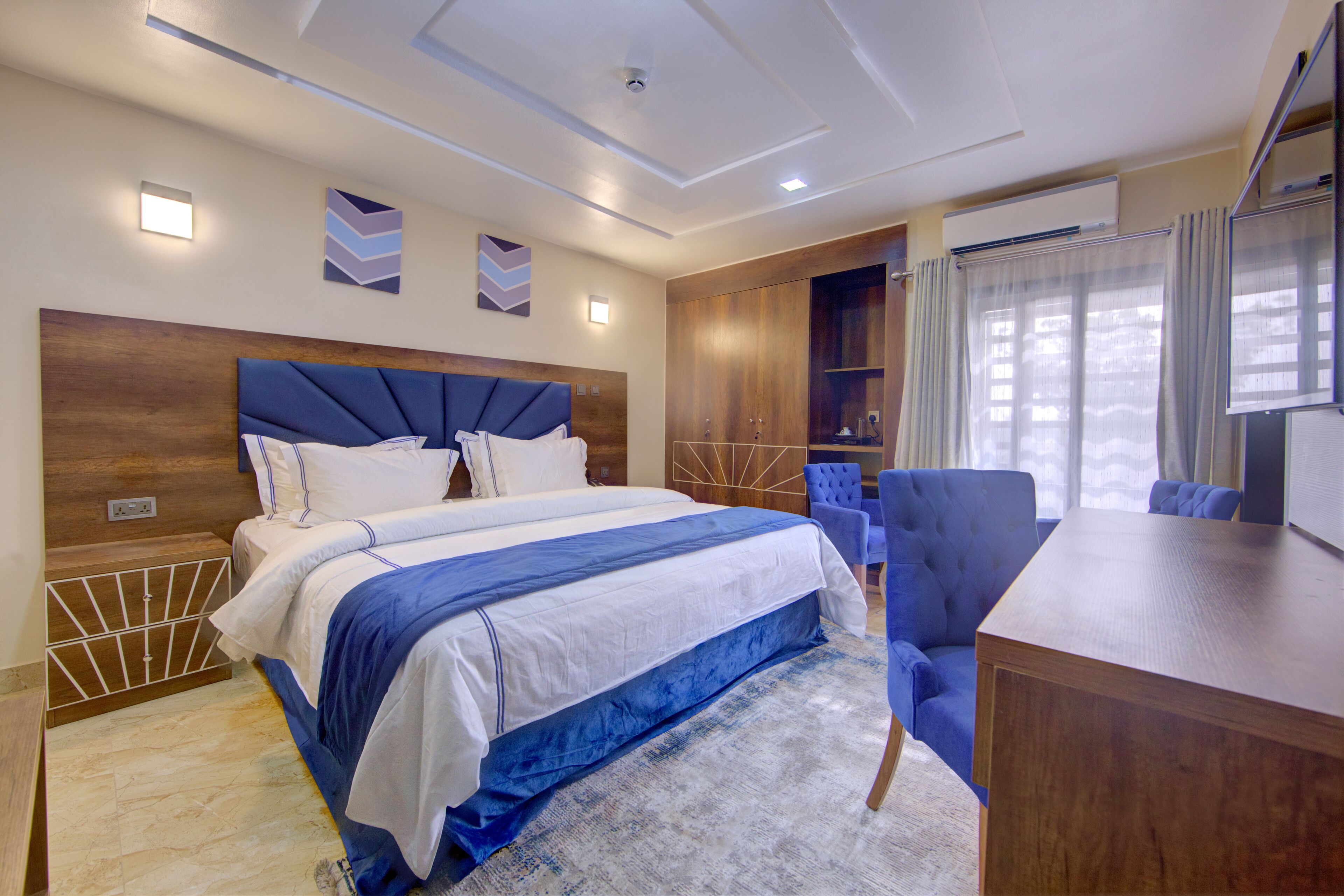 A modern hotel room with a large bed, a desk, and a seating area.