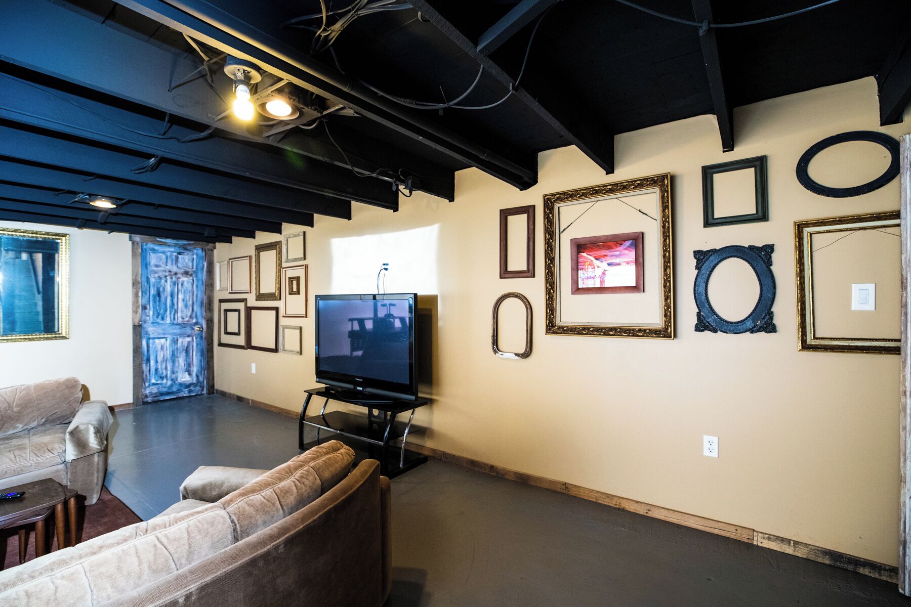 An art gallery with a television on a stand, framed artworks on the walls, and a sofa in the foreground.