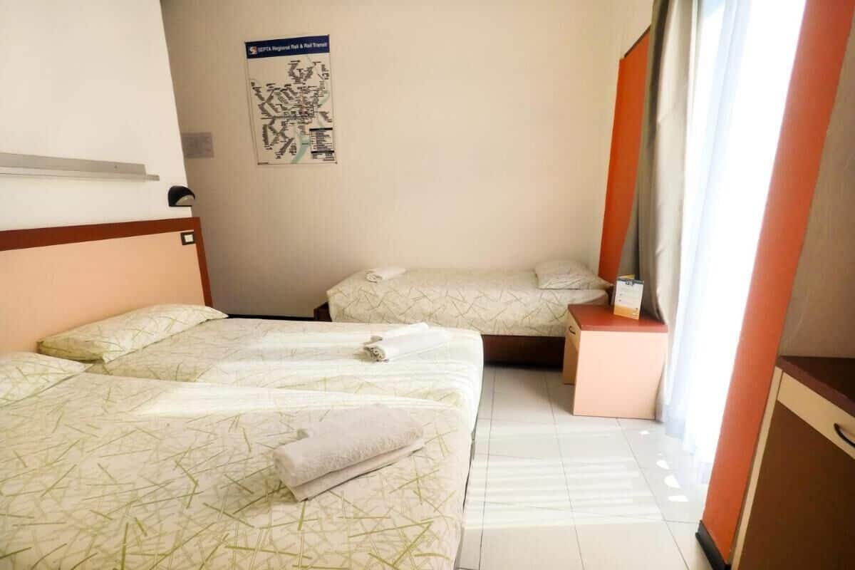 Une chambre d’hôtel avec deux lits, une petite table et une carte accrochée au mur.