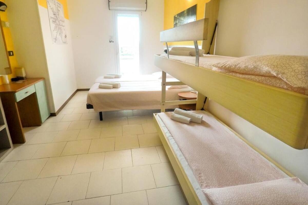 Une chambre avec des lits superposés, un bureau et une chaise.