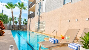 Un espace aménagé au bord de la piscine, avec des chaises longues, une boisson et une plante en pot.