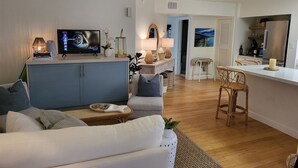 Un salon moderne avec un canapé, un téléviseur et un petit coin repas agrémenté d’un bar.