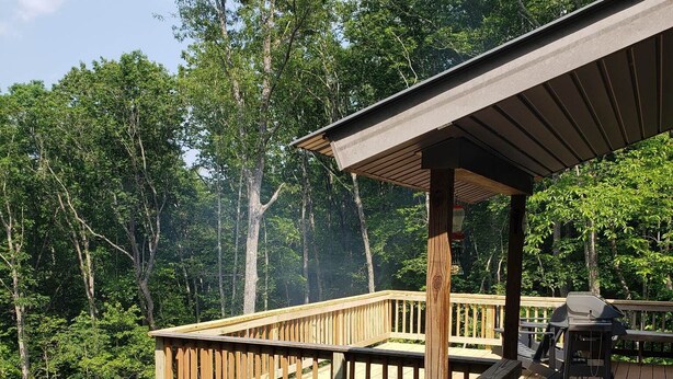 Eine Holzterrasse mit einer Pergola, umgeben von dichtem Wald.