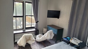 Ein Hotelzimmer mit Bett, Schreibtisch, Sessel, Fernseher und Koffer.
