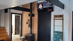 Ein Zimmer mit einer schwarzen Tür, einem Kamin, einem an der Wand montierten Fernseher und einem Holzregal.
