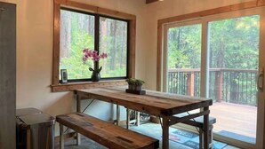 A wooden table with a bench, a vase with flowers, and a view of a balcony with a railing. - Pinecrest Escape (Cold Springs)