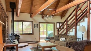 A cozy living room with a fireplace, wooden furniture, and a staircase. - Pinecrest Escape (Cold Springs)